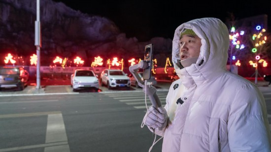 在吉林市阿什哈達霧凇觀景帶，霧凇播報員正在直播。新華社記者 李典 攝